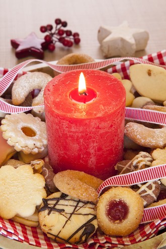 vertikale-aufnahme-einer-grossen-roten-brennenden-kerze-mit-weihnachtsplatzchen-und-verzierungen
